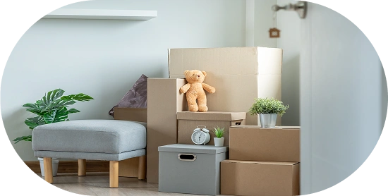 Des cartons de déménagement empilés dans une nouvelle maison, avec des meubles et des objets décoratifs, montrant un emballage organisé pendant le déménagement.